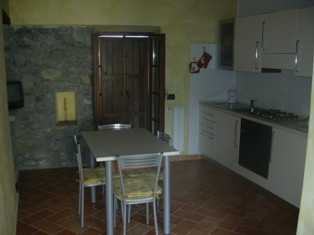 Cucina attrezzata adeguatamente e caratterizzata da porzioni di muro e nicchie in sasso. Clicca per ingrandirla